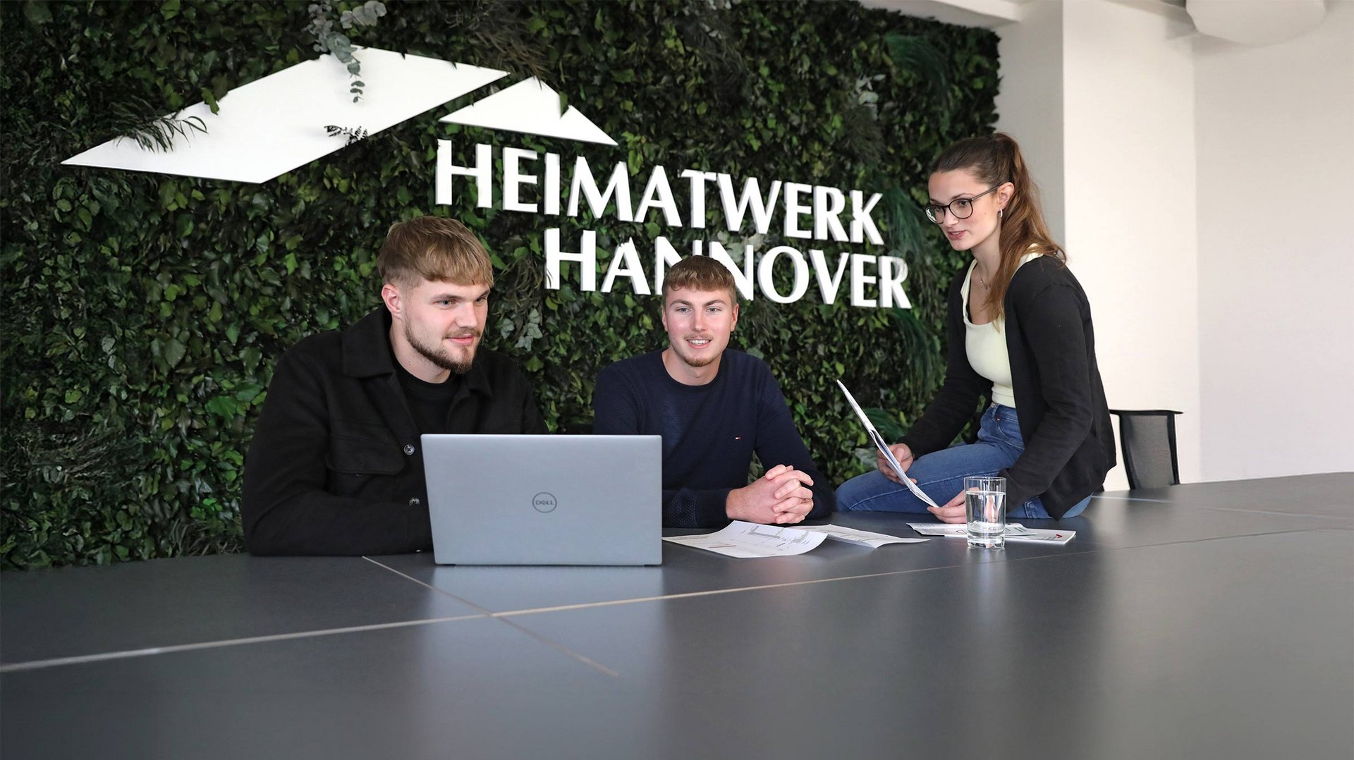 Drei Mitarbeitende vor Laptop im Besprechungsraum