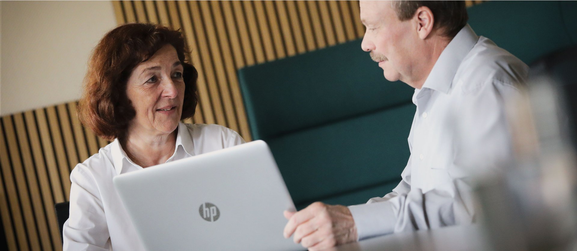 eine Frau und ein Mann sitzen vor einem Laptop