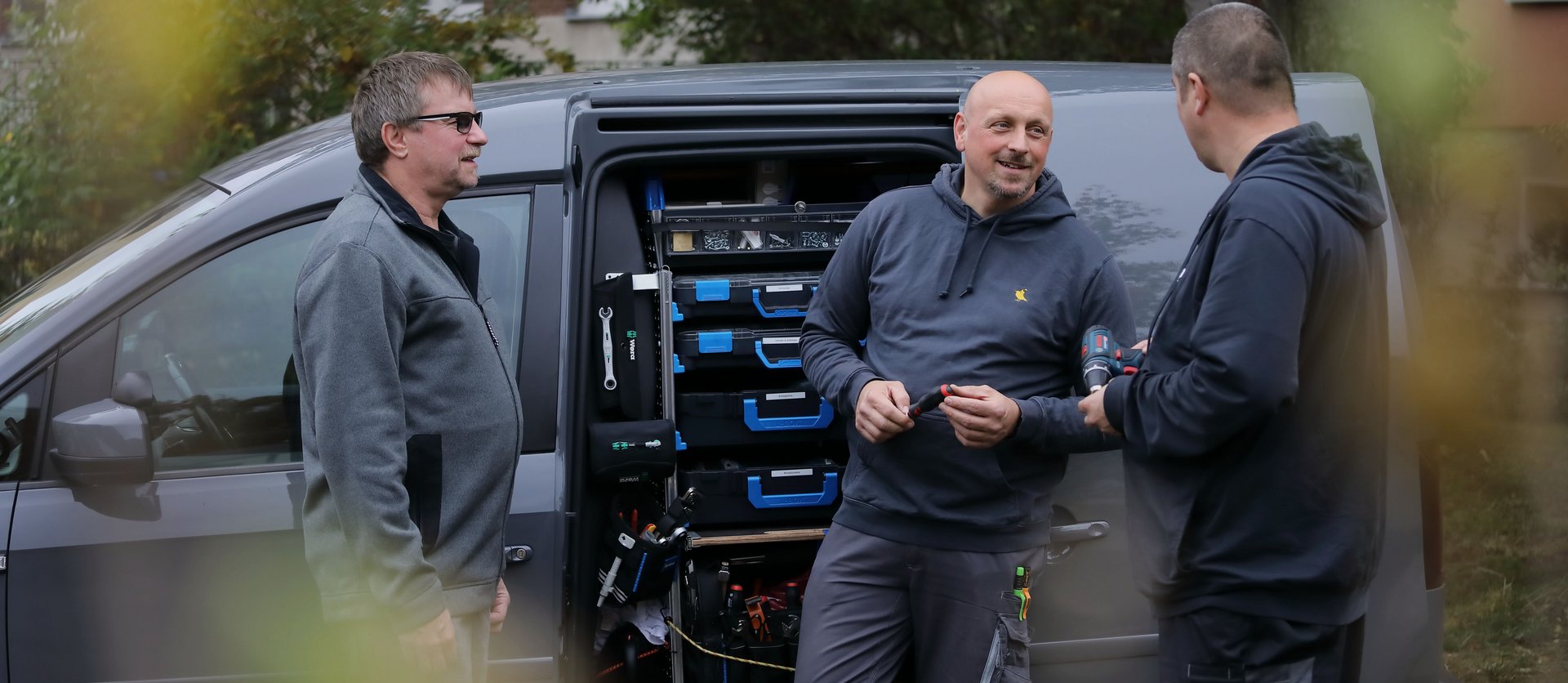 Drei Objektbetreuer vor Servicewagen