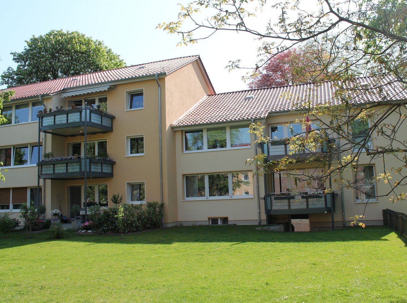 Ansicht vom begrünten Hof auf Balkone und gelbe Fassade