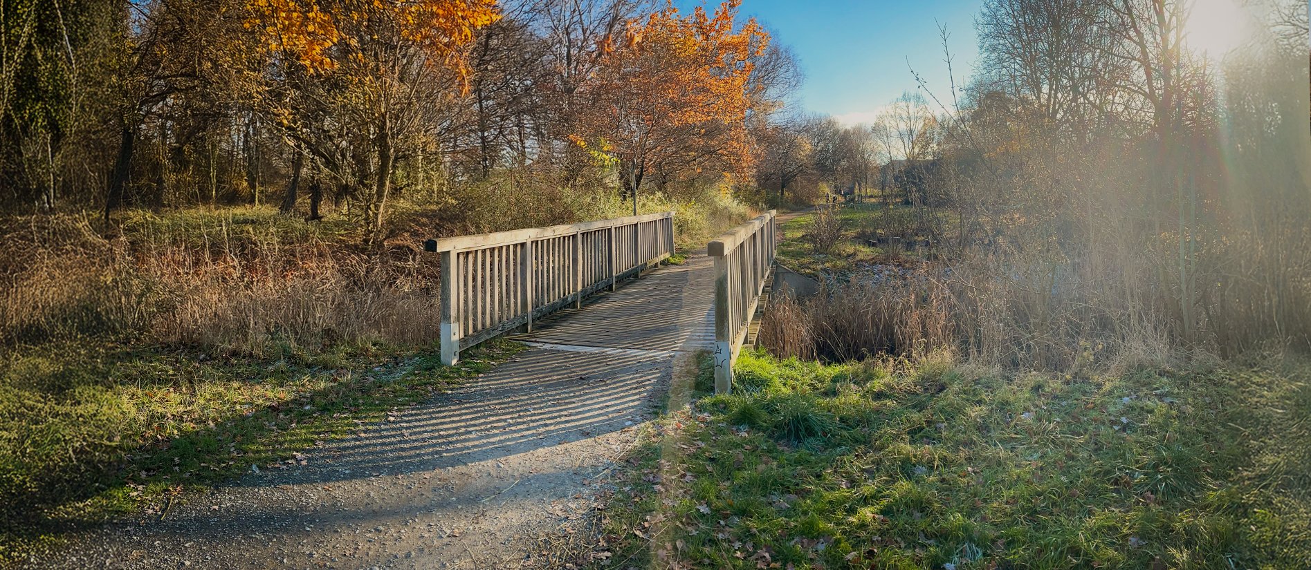 Blick auf eine Fußgängerbrücke mit Holzgeländer in winterlicher Landschaft